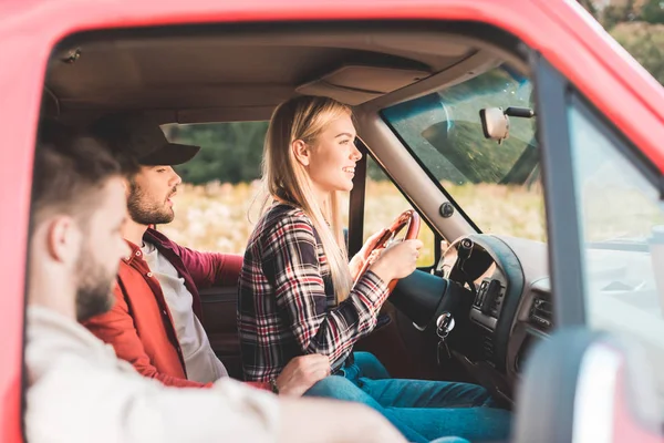 Gruppo di giovani amici che viaggiano in auto e cavalcando sul campo di fiori — Foto stock