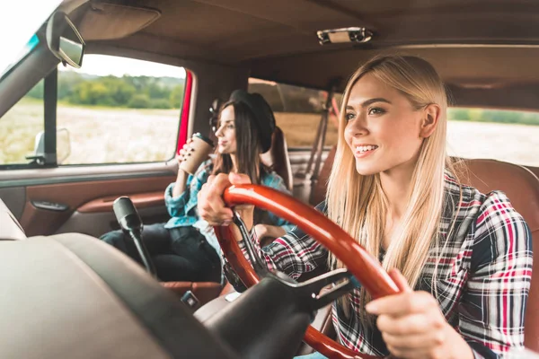 Happy young girlfriends having car trip and riding through fields — Stock Photo