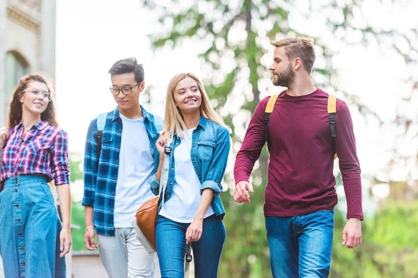 Portrait of group of multiethnic students with backpacks walking in park — Stock Photo