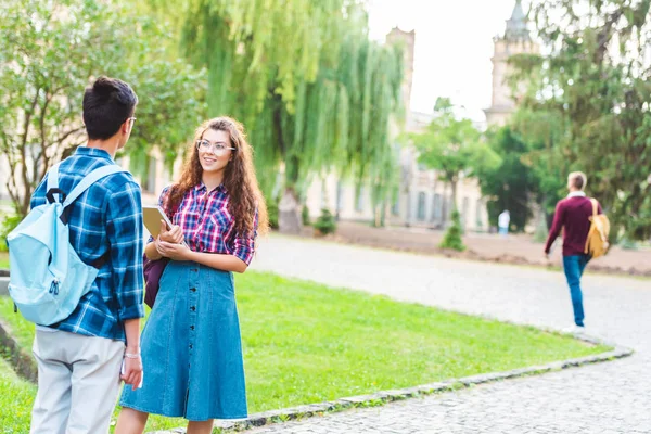 Vue partielle des étudiants multiraciaux ayant une conversation dans le parc — Photo de stock