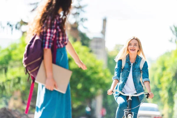 Heureux étudiant regardant camarade de classe tout en vélo sur la rue — Photo de stock