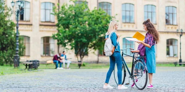 Studenti con bicicletta e quaderni in piedi sulla strada vicino all'università — Foto stock