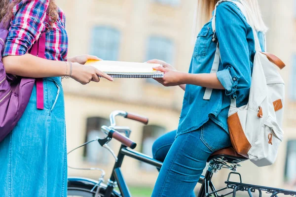Vista parcial de los estudiantes con bicicleta y cuaderno de pie en la calle — Stock Photo