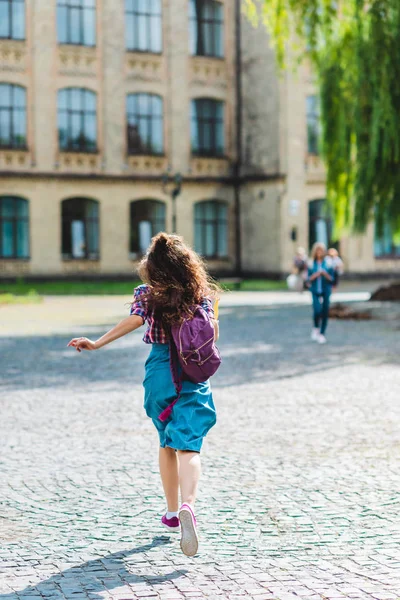 Вид на молодого студента с рюкзаком и блокнотами, бегущего по улице — стоковое фото