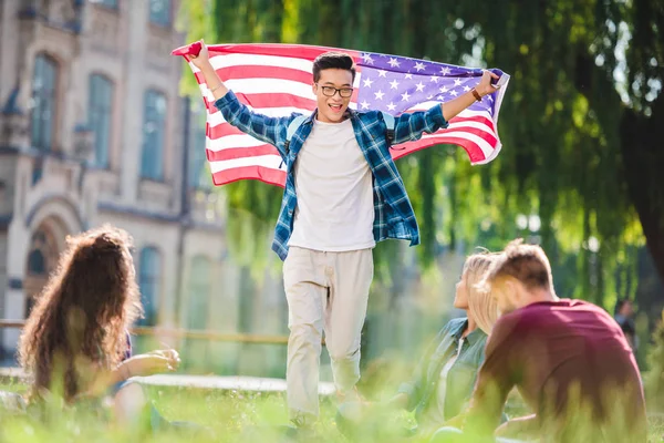 Multicultural students with american flag in summer park — Stock Photo