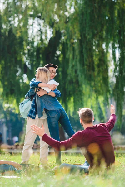 Selective focus of multicultural students on green grass in summer park — Stock Photo