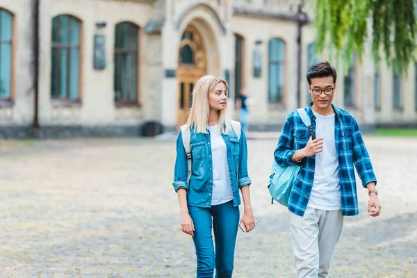 Selective focus of multicultural students with backpacks walking on street — Stock Photo