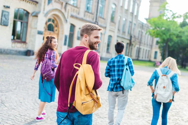 Visão traseira de estudantes com mochilas andando na rua juntos — Fotografia de Stock