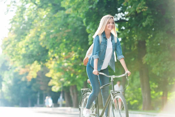 Estudiante sonriente con mochila montar en bicicleta en la calle - foto de stock