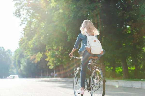 Вид ззаду студента з рюкзаком їзда на велосипеді на вулиці — стокове фото