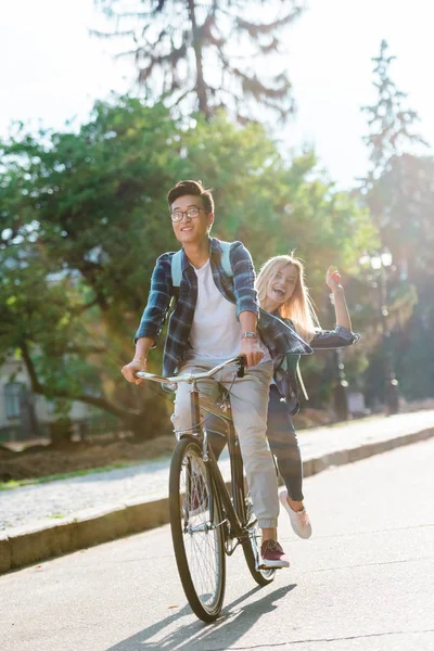 Felizes estudantes multiétnicos andar de bicicleta juntos na rua — Fotografia de Stock