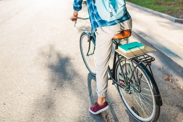 Vista parziale dello studente con zaino in sella alla bicicletta sulla strada — Foto stock