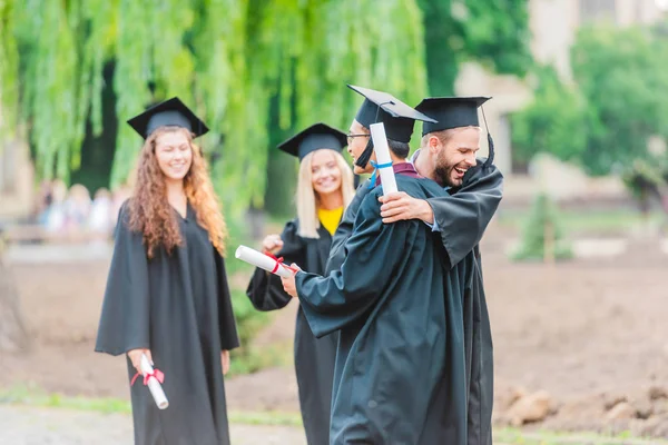 Portrait of happy multiracial graduates with diplomas on street — Stock Photo