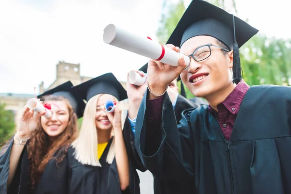 Enfoque selectivo de los graduados multiculturales con diplomas en el parque - foto de stock