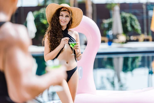 Immagine ritagliata di fidanzata che tiene il bicchiere di cocktail e guarda il fidanzato vicino alla piscina — Foto stock