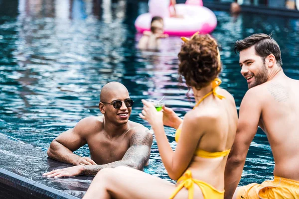 Fröhliche junge Freunde unterhalten sich am Pool — Stockfoto