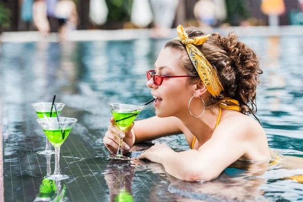 Atractiva joven bebiendo cóctel en la piscina — Stock Photo