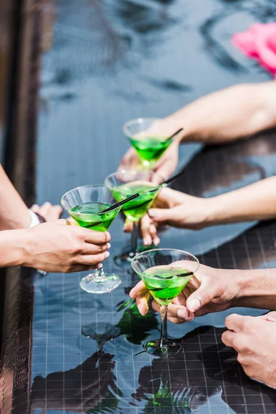 Abgeschnittenes Bild von Freunden, die mit Cocktails in der Nähe des Swimmingpools klirren — Stockfoto