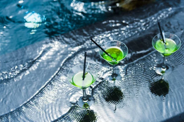 Vue grand angle des verres avec pailles à boire dans la piscine — Photo de stock