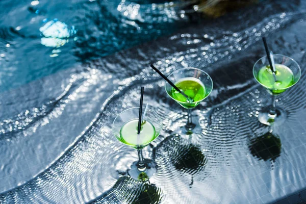 Vista de ángulo alto de vasos con pajitas para beber en la piscina - foto de stock