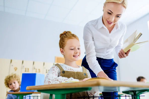 Schöne Lehrerin hilft kleine Schülerin während des Unterrichts — Stockfoto