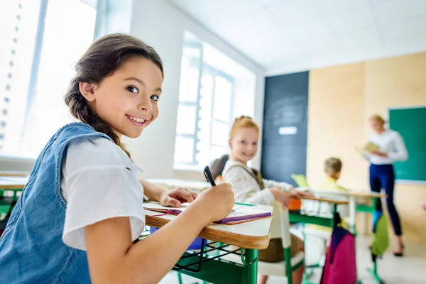 Petites écolières regardant la caméra pendant les cours à l'école — Photo de stock