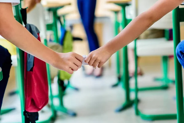 Tiro recortado de alunos que passam mensagem no papel durante a aula — Fotografia de Stock