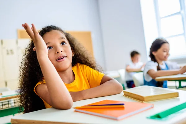 Afro-américaine écolière levant la main pour répondre aux questions des enseignants pendant la leçon — Photo de stock