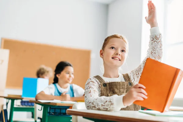 Colegiala levantando la mano para responder a la pregunta de los profesores durante la lección - foto de stock