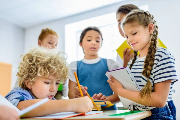 Alunni scrivere fuori compiti del loro compagno di classe durante la pausa — Foto stock