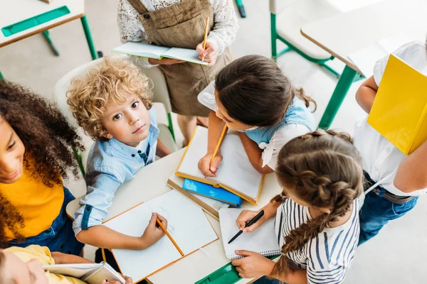 Vista ad alto angolo di scolari che cancellano i compiti del loro compagno di classe durante la pausa — Foto stock