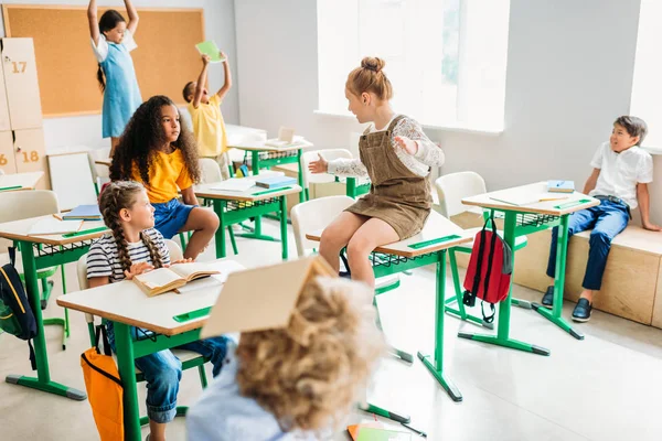 Grupo de escolares que se divierten en el aula durante el descanso - foto de stock