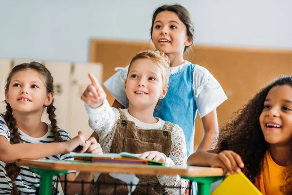 Heureux écolières pointant quelque part à salle de classe — Photo de stock