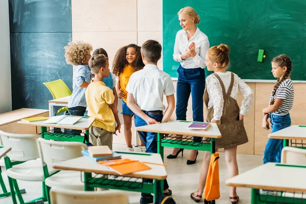 Gruppe von Klassenkameraden steht um Lehrer im Klassenzimmer — Stockfoto
