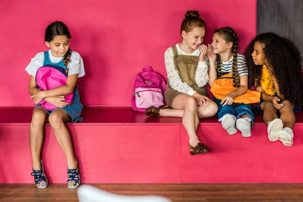 Group of schoolgirls laughing and gossiping on their classmate at school — Stock Photo