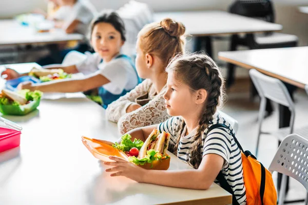 Group of schoolgirls taking lunch at school cafeteria together — Stock Photo