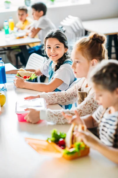 Pequenas alunas felizes almoçando na cafetaria da escola — Fotografia de Stock