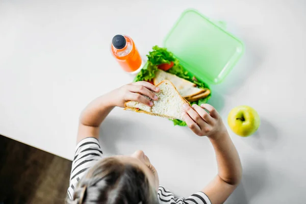 Top view of schoolgirl eating sandwich from lunch box — Stock Photo