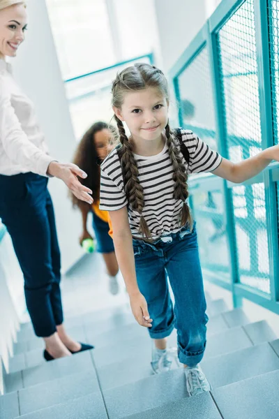 Высокий угол зрения школьниц, идущих наверх с учителем в школьном коридоре — стоковое фото