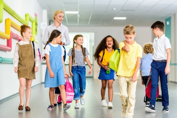Група щасливих однокласників, що ходять по шкільному коридору — стокове фото