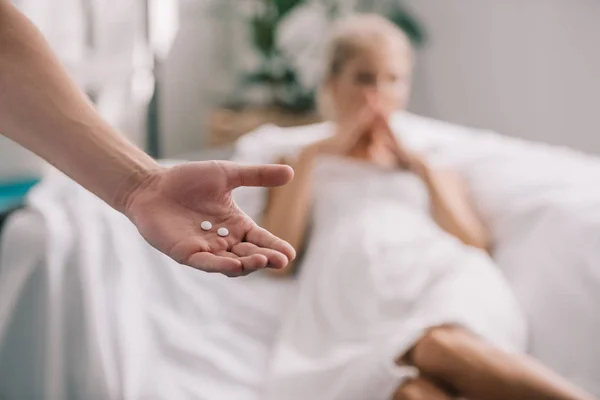 Schnappschuss von Mann mit Tabletten in der Hand und schwangerer Frau, die sich zu Hause unwohl fühlt — Stockfoto
