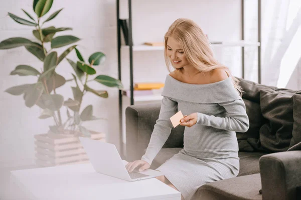 Donna incinta con carta di credito e laptop acquistare beni online a casa — Foto stock