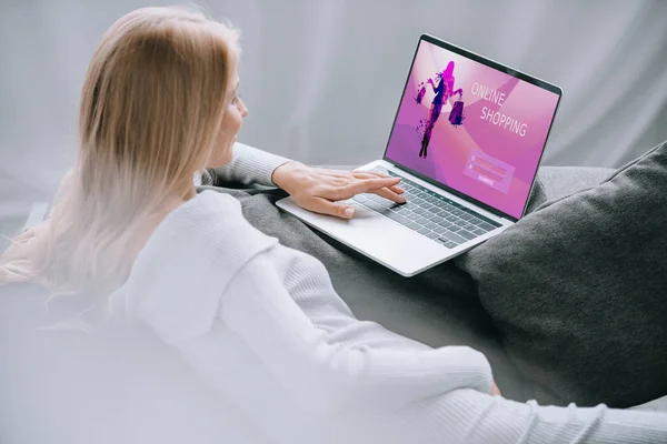 Беременная женщина с помощью ноутбука с онлайн торговый знак на экране на диване дома — стоковое фото