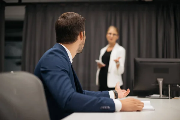 Selective focus of businesswoman with smartphone and colleague at workplace discussing project together in office — Stock Photo