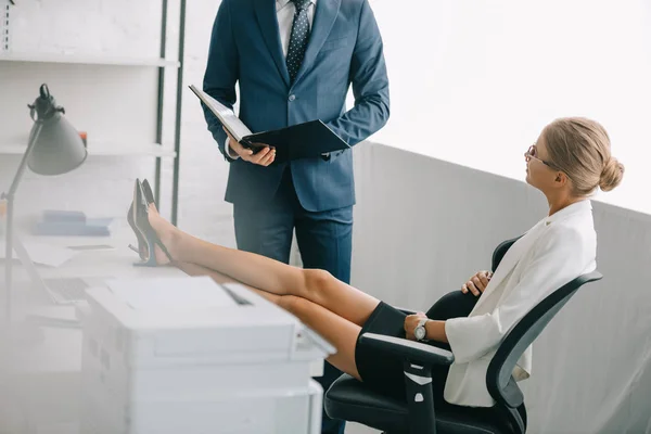 Geschäftsmann mit Dokumenten und schwangere Kollegin diskutieren über Arbeit am Arbeitsplatz im Büro — Stockfoto