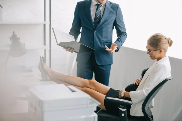 Uomo d'affari con documenti e collega incinta che discute di lavoro sul posto di lavoro in ufficio — Foto stock