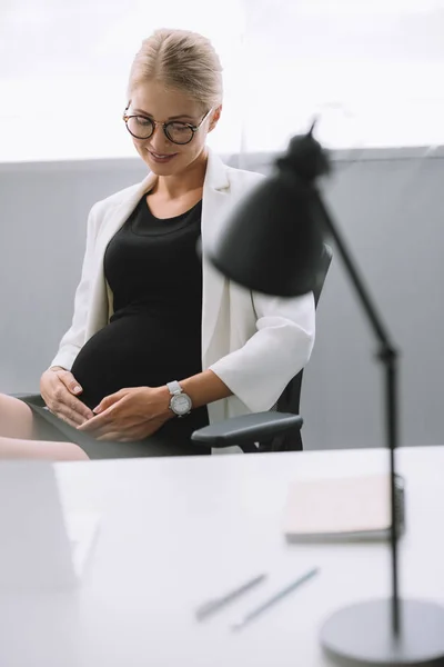 Portrait of pregnant businesswoman in eyeglasses at workplace in office — Stock Photo
