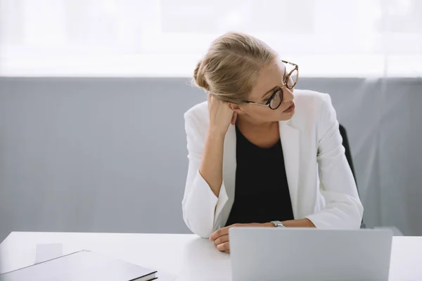 Ritratto di donna d'affari in occhiali seduta sul posto di lavoro con computer portatile in ufficio — Foto stock