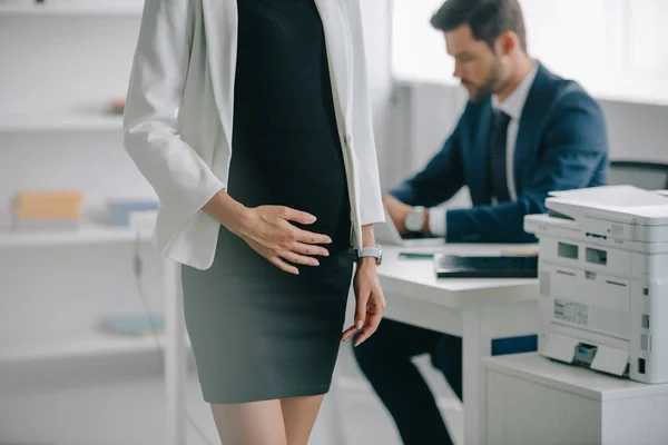 Visión parcial de la mujer de negocios embarazada y colega en el lugar de trabajo en la oficina - foto de stock