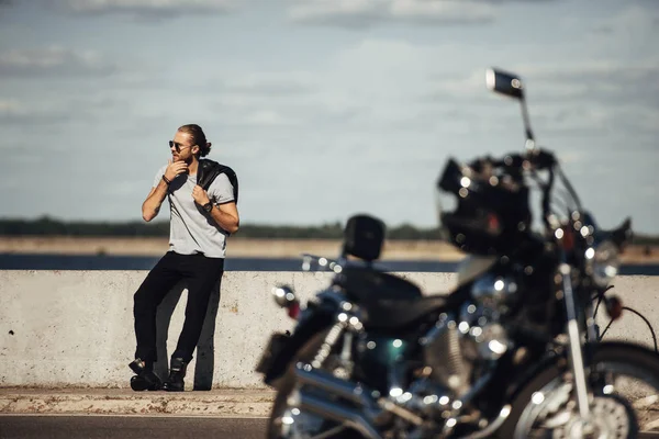 Selective focus of young biker with motorbike on foreground — Stock Photo